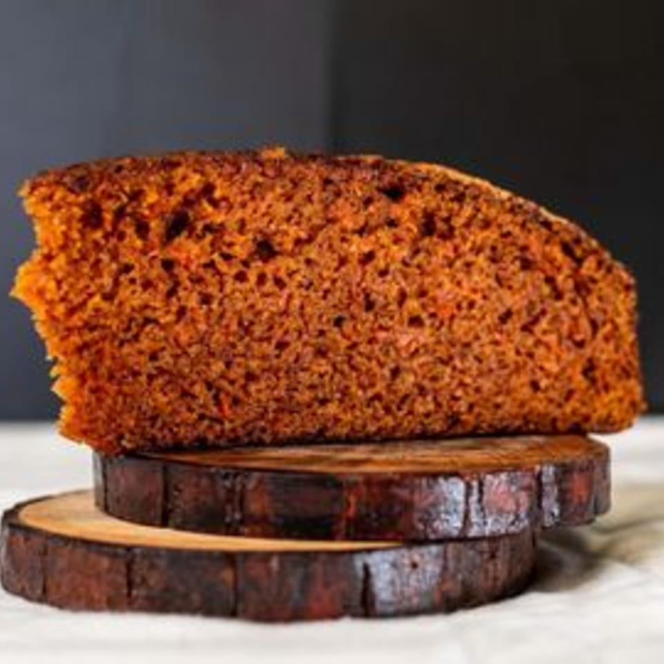 A slice of Caribbean spice cake on two wooden coasters.