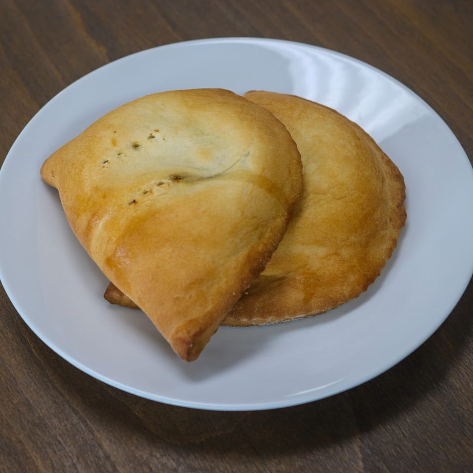 Two golden-brown Caribbean Spice! patties, one slightly overlapping the other, on a white plate.