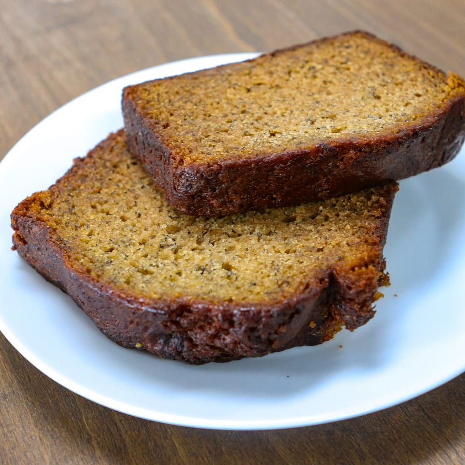 Two slices of Caribbean spice bread, golden brown and moist, on a white plate.